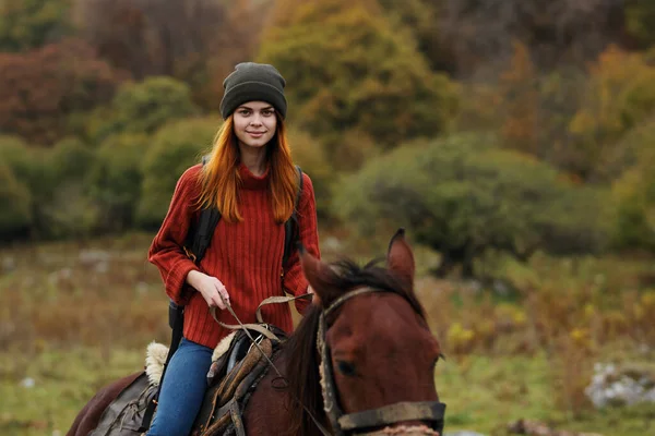 Woman hiker with backpack rides a horse friendship travel mountains — Stock Photo, Image