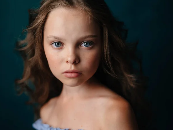 Portrait d'une belle petite fille en robe de soleil sur fond sombre gros plan — Photo