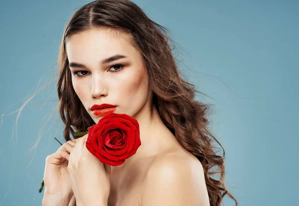 Młoda kobieta z czerwoną różą w pobliżu cienia twarzy na powiekach niebieski model tła — Zdjęcie stockowe