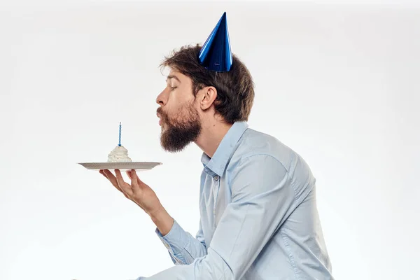 Un homme avec une barbe tient un gâteau dans sa main sur un fond clair anniversaire — Photo