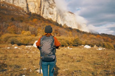 Kot şapkalı sırt çantalı bir gezgin doğa dağlarında yürüyor.