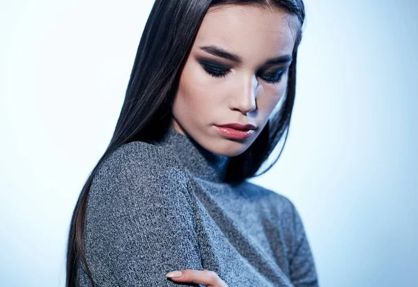 Πορτρέτο μιας ελκυστικής γυναίκας σε ένα ελαφρύ φόντο σε ένα γκρι πουλόβερ και μακιγιάζ στο πρόσωπό της — Φωτογραφία Αρχείου