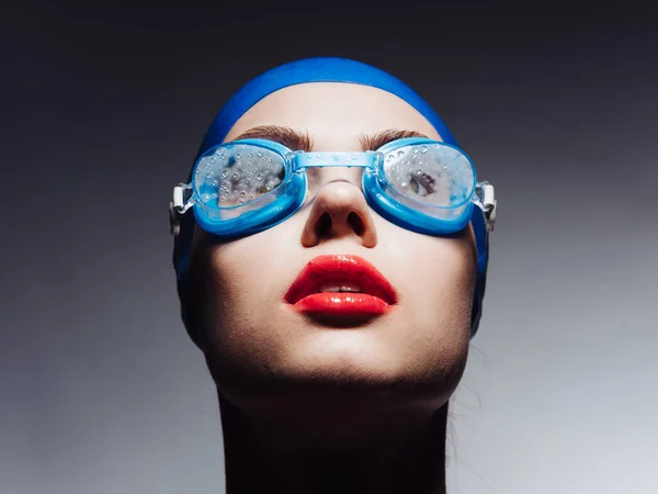 Kırmızı dudaklı, mavi yüzme şapkalı ve gözlüklü sporcu kadın kırpık manzaraya bakıyor. — Stok fotoğraf