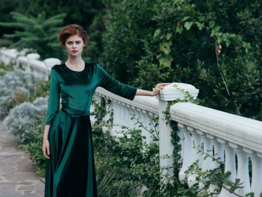 Yeşil elbiseli bir kadın açık havada romantizm içinde yürüyor.