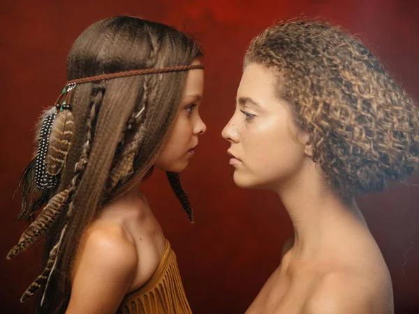 美しいです女の子とともに羽で彼女の髪と女性aborigines赤背景家族インドの部族 — ストック写真
