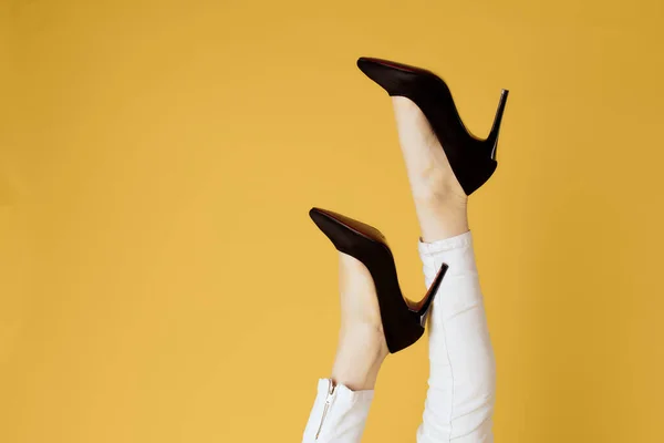 Inverterade kvinnliga ben svarta skor attraktiv utseende gul bakgrund shopping — Stockfoto