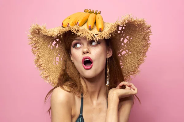 Kobieta w słomce kapelusz banany gospodarstwa owoce Egzotyczny strój kąpielowy różowy tło — Zdjęcie stockowe