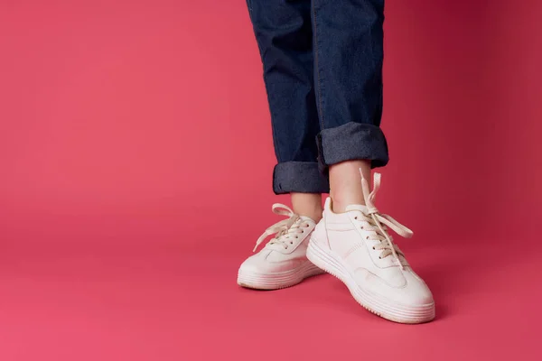 Weibliche Füße weiße Turnschuhe Straße Mode Studio rosa Hintergrund — Stockfoto