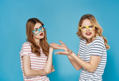 Çizgili tişörtlü iki kız kardeş iletişim duyguları mavi arka planda kavga ediyor