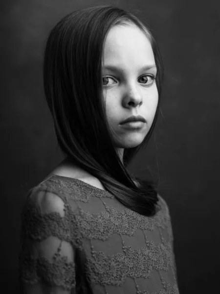 Portrait d'une petite fille sur un fond sombre robe modèle vue recadrée noir et blanc photographie — Photo