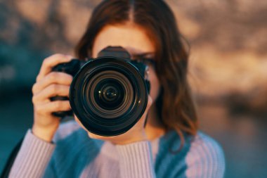 Nehir kenarındaki dağlarda kameralı kızıl saçlı bir kadın. Yüksek kalite fotoğraf