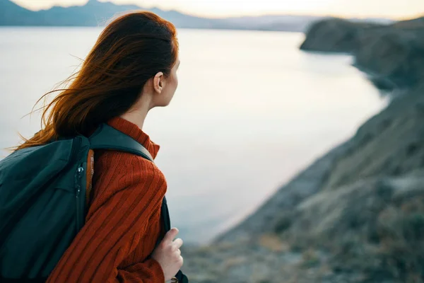 Viaggiatore felice in un maglione e con uno zaino guardare il mare in lontananza e montagne natura aria fresca — Foto Stock