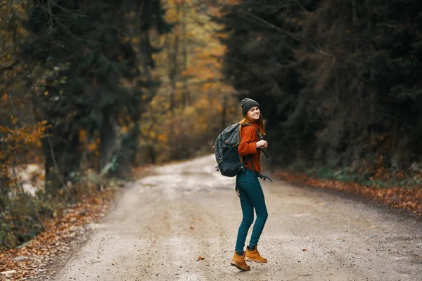 Viajante feliz com mochila caminha na estrada na floresta de outono — Fotografia de Stock