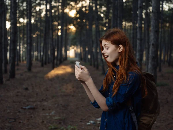 Mujer feliz en bosque de pinos con teléfono móvil navegador modelo turístico —  Fotos de Stock