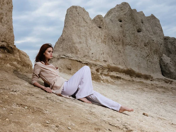 Vrouw met lichte kleren op het zand bij de rotsen en hoge stenen — Stockfoto