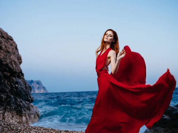 Γυναίκα σε κόκκινο φόρεμα βραχώδη βουνά ωκεανό σε εξωτερικούς χώρους — Φωτογραφία Αρχείου
