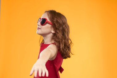 Siyah gözlüklü kız kırmızı elbise çocukluk eğlencesi sarı arka plan