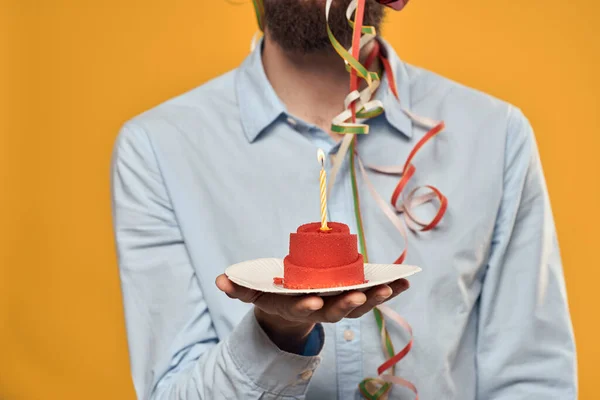 Ένας άνθρωπος που κρατά ένα κέικ σε ένα πιάτο και ένα κερί από πάνω απομονωμένο φόντο — Φωτογραφία Αρχείου