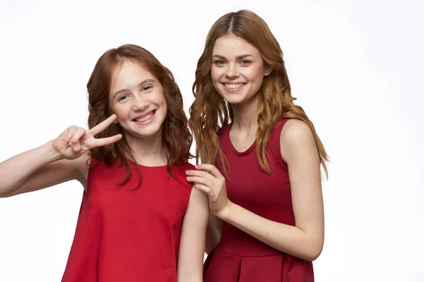 Fröhlich Mutter und Tochter neben roten Kleidern Umarmungen Lifestyle Licht Hintergrund Lächeln — Stockfoto