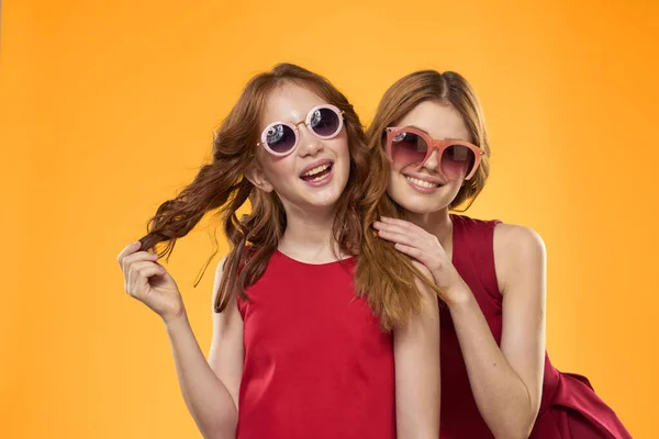 Dos hermanas y divertidas gafas de sol moda Amistad fondo amarillo familia — Foto de Stock