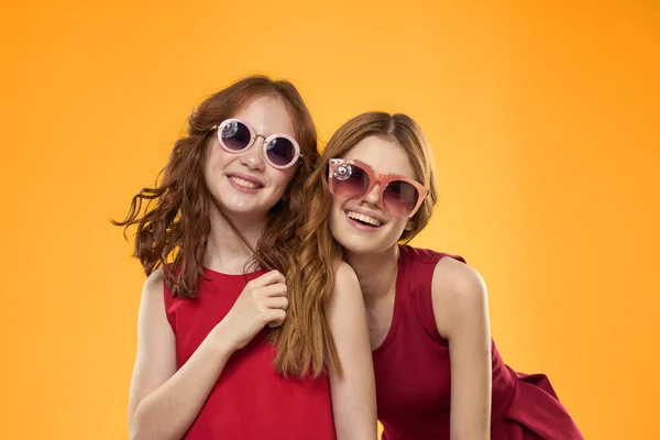 Dos hermanas y divertidas gafas de sol moda Amistad fondo amarillo familia — Foto de Stock