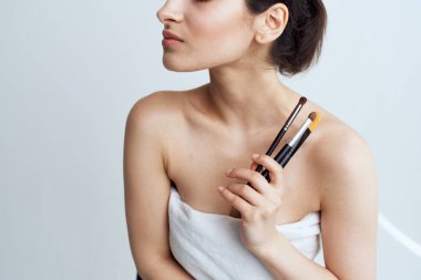 Güzel bir kadın çıplak omuzlarıyla makyaj malzemelerini temizler.