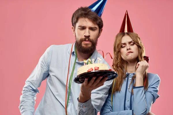 Party man and woman with cake on pink background corporate birthday