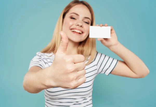 Femme heureuse sur un fond bleu gestes avec ses mains et une carte de visite dans sa main — Photo