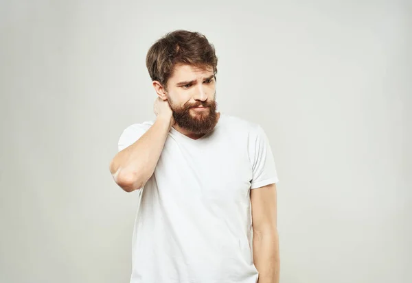 En man i vit T-shirt gester med händerna på en ljus bakgrund beskärs bild av känslor modell — Stockfoto