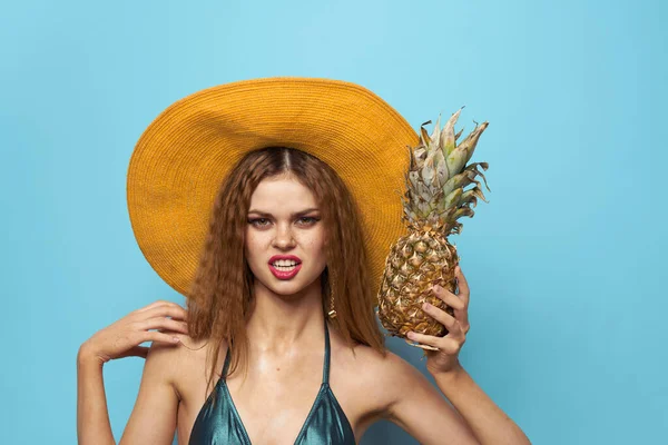 Kvinna i strand hatt ananas innehav baddräkt exotiska frukter blå bakgrund semester — Stockfoto