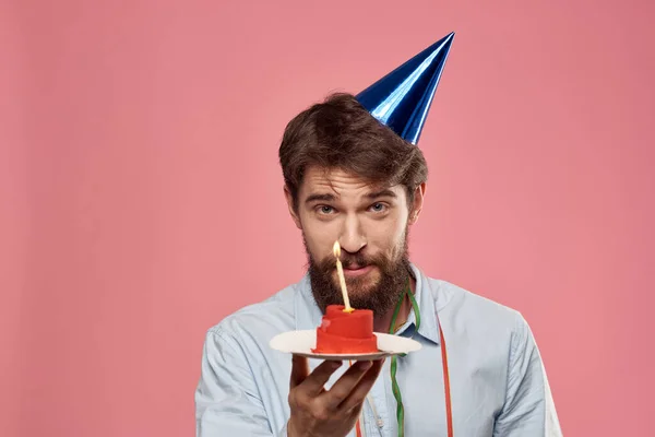 Alegre barbudo hombre en un festivo sombrero cumpleaños emociones rosa fondo — Foto de Stock