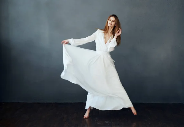 Encantadora dama en un vestido blanco sobre un fondo gris danza gesticulando con sus manos modelo — Foto de Stock