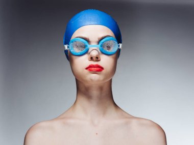 Kırmızı dudaklı, mavi yüzme şapkalı ve gözlüklü sporcu kadın.