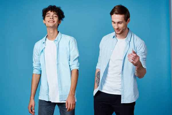 Amici in abiti identici su sfondo blu gesticolando con le mani ritagliato vista — Foto Stock