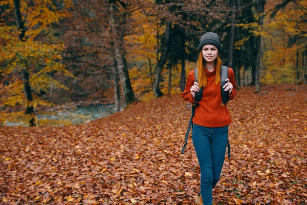 Reiziger met rugzak in de herfst bos en hoed trui jeans gevallen bladeren meer bomen — Stockfoto
