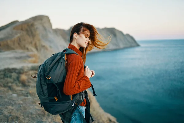 Жінка в светрі з рюкзаком ходить в природі в горах біля моря — стокове фото