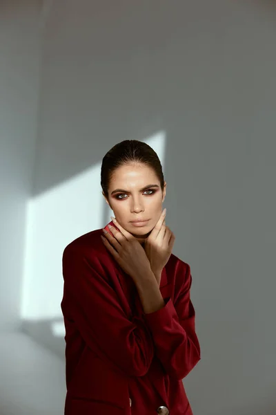 Morena bonita brilhante maquiagem mãos perto de face vermelho casaco moda glamour — Fotografia de Stock