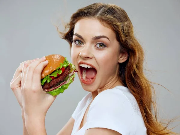 Mulher faminta com hambúrguer na mão ampla boca aberta retrato close-up — Fotografia de Stock