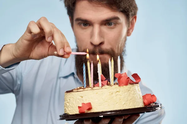 Hombre con un plato de pastel y una vela festiva fondo azul gorra fiesta corporativa — Foto de Stock