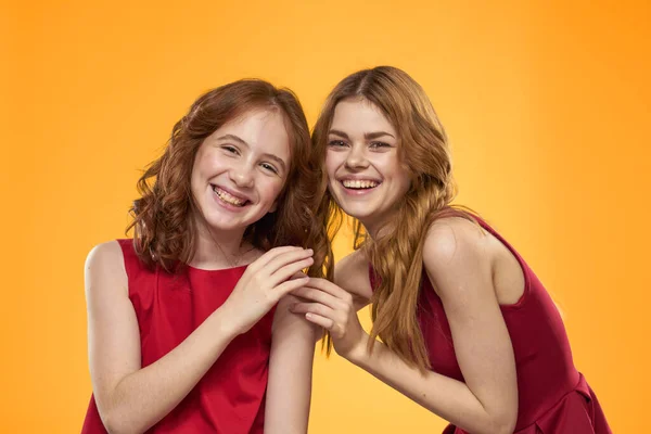 Mamá e hija en vestidos rojos entretenimiento estilo de vida fondo amarillo —  Fotos de Stock