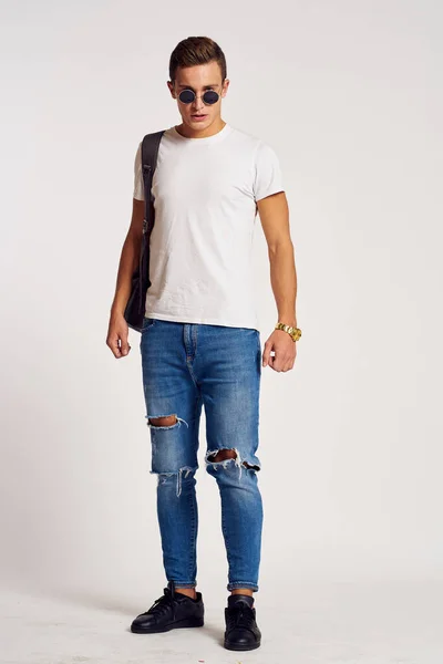 Ein Mann mit Rucksack auf dem Rücken in Jeans-T-Shirt, Turnschuhen und Brille im Gesicht — Stockfoto