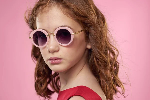 女の子とともに巻き毛黒丸メガネ楽しい赤ドレスピンクの背景 — ストック写真