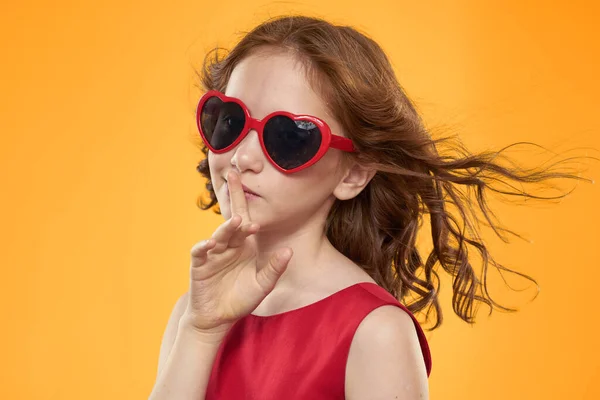 Chica en gafas negras vestido rojo infantil divertido fondo amarillo — Foto de Stock