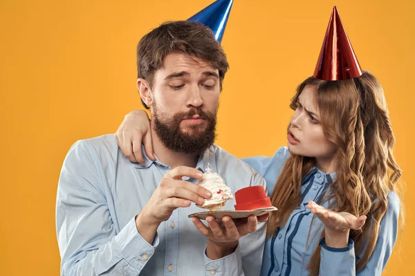 Birthday party mężczyzna i kobieta zabawy żółty tło czapka wakacje — Zdjęcie stockowe