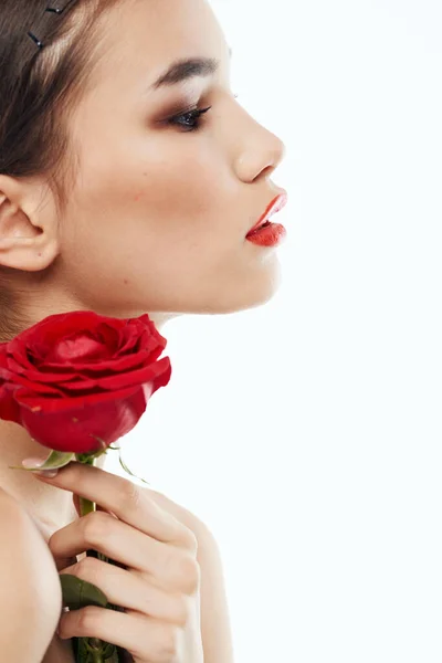 Boční pohled na romantickou ženu s červenou květinou v blízkosti obličeje — Stock fotografie