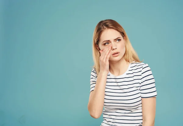 Puzzled woman touches her face with hands on a blue background model stress emotions