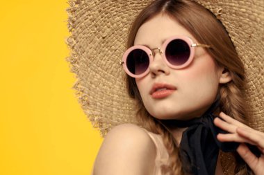 Güneş gözlüklü ve şapkalı güzel bir kadın yaz seyahati görüntüsü sarı arka plan