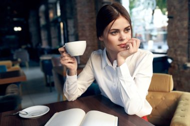 Lokantada elinde not defteri ve elinde bardakla bir kadın.