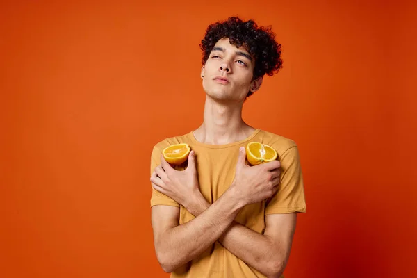 Χαρούμενος τύπος με σγουρά μαλλιά και κρατώντας ένα πορτοκαλί απομονωμένο φόντο — Φωτογραφία Αρχείου