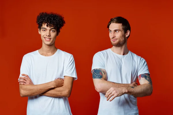 흰색 티셔츠 건축 팀에서 일하는 두 친구가 빨간 배경에 감정을 느낀다 — 스톡 사진